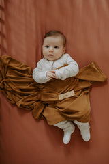 Bébés dans un lit avec doudou couleur caramel.