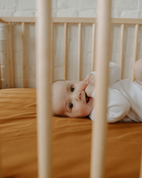 Bébé dans un lit avec literie couleur safran.