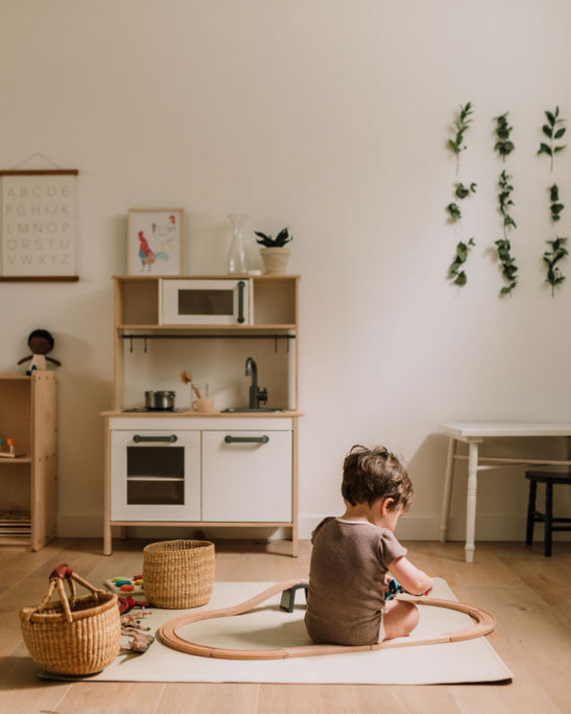 Enfant qui joue sur un tapis de cuir végan carré côté crème.