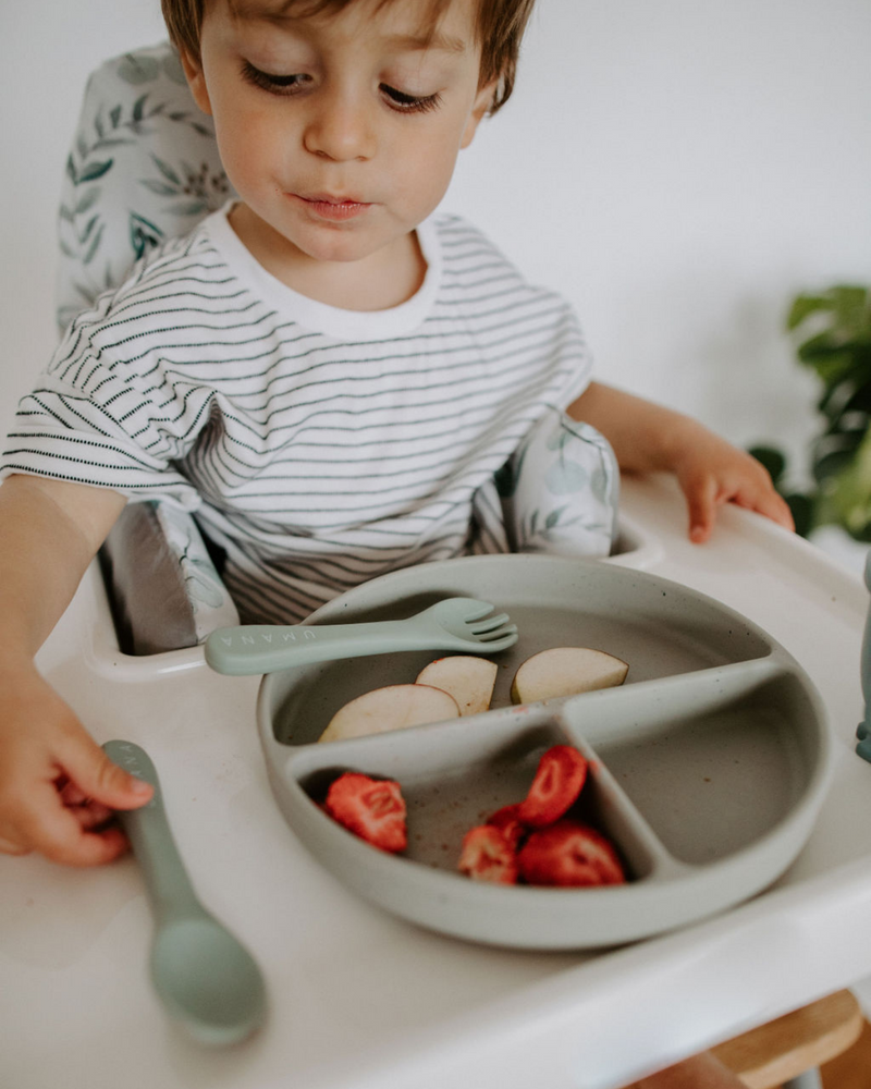 Enfant qui joue avec vaisselle en silicone couleur pistache.
