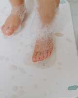 Tapis de bain rigide en diatomite couleur terrazzo avec petits pieds d'enfant.