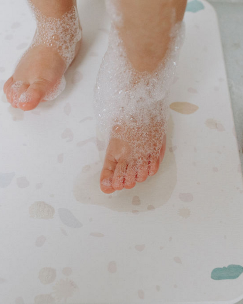 Tapis de bain rigide en diatomite couleur terrazzo avec petits pieds d'enfant.